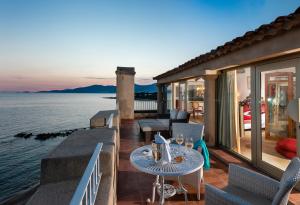 a patio with a table and chairs and the water at Hotel Le Maquis in Porticcio