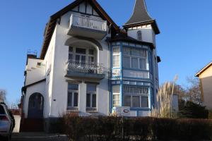 a white and blue house with a turret at Pension Lotte in Kühlungsborn