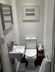 La salle de bains est pourvue de toilettes blanches et d'un lavabo. dans l'établissement Stylish Boatwright Cottage moments from beach by Whitstable-Holidays, à Whitstable