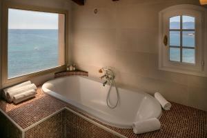 a bath tub in a bathroom with a large window at Hotel Le Maquis in Porticcio