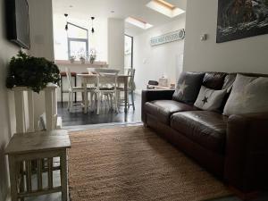 a living room with a brown couch and a table at Stylish Boatwright Cottage moments from beach by Whitstable-Holidays in Whitstable