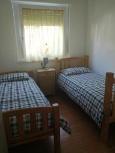 2 camas en un dormitorio pequeño con ventana en Appartamento luminoso, giardino, vista Dolomiti., en Baselga di Pinè
