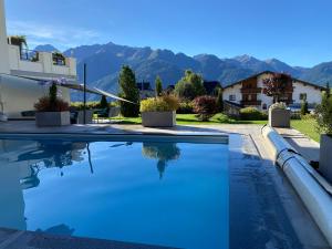 a swimming pool in a villa with mountains in the background at Apart Alpenstern in Fiss