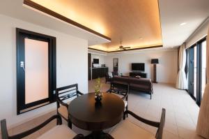 uma sala de estar com uma mesa e cadeiras e um sofá em Kafuu Resort Fuchaku Condo Hotel em Onna