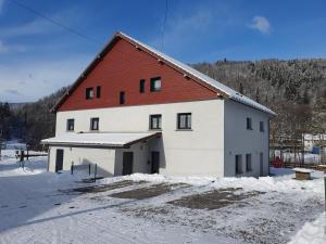 un gran edificio blanco con techo rojo en la nieve en appart Renard 4 étoiles, en Cornimont