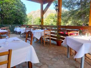 um restaurante com mesas brancas e cadeiras com montanhas ao fundo em auberge de tesa em Occhiatana