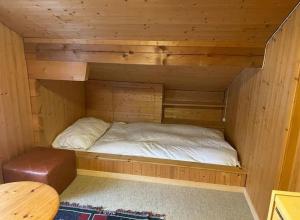 a small bed in a wooden cabin with a table at Chalet Kuckuk in Habkern