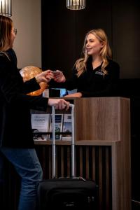 Deux femmes serrent la main à un comptoir avec une valise dans l'établissement Hotel Reynaert Bv, à Hulst