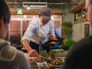 a chef preparing food in a restaurant kitchen at HOSTEL OE in Yoshinogawa