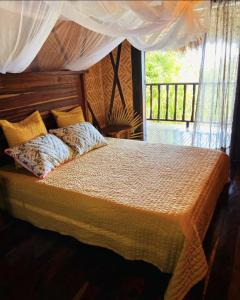 1 dormitorio con cama con almohadas y ventana en Le 19 des Hauts Manguiers, en Nosy Be