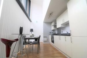 a kitchen with white cabinets and a table and chairs at Lovely Modern Central & Spacious in Liverpool