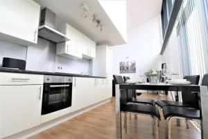 a kitchen with white cabinets and a black table and chairs at Lovely Modern Central & Spacious in Liverpool