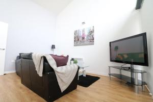 a living room with a couch and a flat screen tv at Lovely Modern Central & Spacious in Liverpool