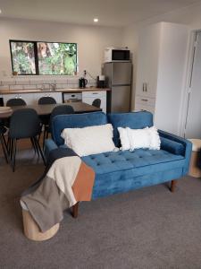 a blue couch in a living room with a kitchen at Kea Retreat in Franz Josef