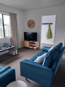 a living room with a blue couch and a tv at Kea Retreat in Franz Josef