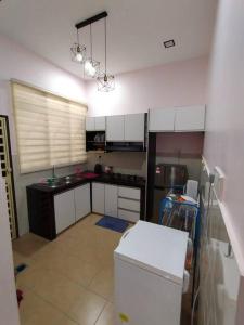 a kitchen with white cabinets and a white refrigerator at KS Villa Homestay KKB in Kampong Peruntun