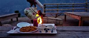 una persona está cocinando comida en una mesa con una bandeja de comida en Kashmir Eagle Heights Cottage & Restaurant by LMC, en Muzaffarabad