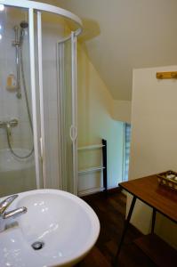 La salle de bains est pourvue d'une douche et d'un lavabo blanc. dans l'établissement La Quinta, belle maison en pierres avec jardins, à Asnelles