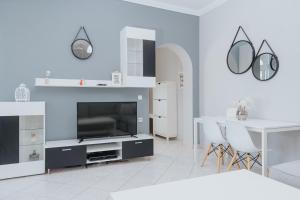 uma sala de estar branca com uma televisão e uma mesa em Serotonin em Zakynthos Town