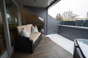 Hochwertiges Apartment / 120m² / Dachterrasse / Parking في درسدن: شرفة مع أريكة ونافذة