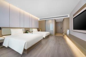 済南市にあるAtour Hotel Jinan West Railway Stationのベッド2台、薄型テレビが備わるホテルルームです。
