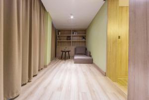 a hallway with curtains and a chair and a table at Atour Hotel Qingdao Olympic Sailing Center May Fourth Square in Qingdao