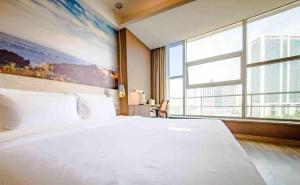 ein Schlafzimmer mit einem großen weißen Bett und einem großen Fenster in der Unterkunft Atour Hotel Jinan High-tech Wanda Plaza Tiancheng Road in Jinan