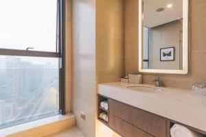La salle de bains est pourvue d'un lavabo, d'un miroir et d'une fenêtre. dans l'établissement Atour Hotel Guanyin Bridge Chongqing, à Chongqing