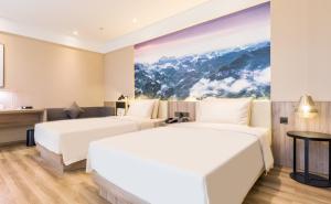 two beds in a hotel room with a painting on the wall at Atour Hotel Guangzhou Jiangtai Road Station in Guangzhou