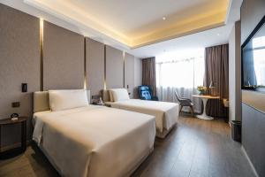 a hotel room with two beds and a television at Atour Hotel Wushan Road Fuzhou Three Lanes and Seven Alleys in Fuzhou