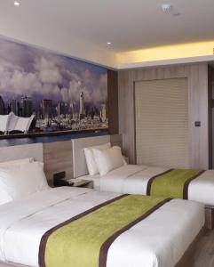 two beds in a hotel room with a painting on the wall at Atour Hotel Qingdao Olympic Sailing Center May Fourth Square in Qingdao