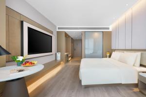 a hotel room with a large white bed and a tv at Atour Hotel Jinan West Railway Station in Jinan