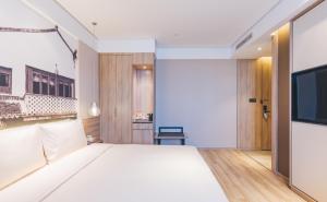 a bedroom with a large white bed and a flat screen tv at Atour Hotel Shanghai New International Expo Center Maglev Station in Shanghai