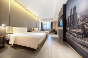ein Hotelzimmer mit 2 Betten und einem Gemälde an der Wand in der Unterkunft Atour Hotel Chongqing Jiangbei International Airport Huixing Light Rail Station in Chongqing
