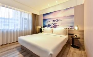 een wit bed in een kamer met een groot raam bij Atour Hotel Dalian Development Zone Jinma Road in Dalian