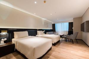 a hotel room with two beds and a desk and a table at Atour S Hotel Shanghai Lujiazui Financial Center in Shanghai