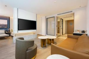 a living room with a couch and a tv at Dalian Airport Yingke Road Atour Hotel in Dalian