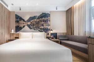 長沙市にあるAtour Hotel Changsha IFC Centerのベッドとソファ付きのホテルルーム