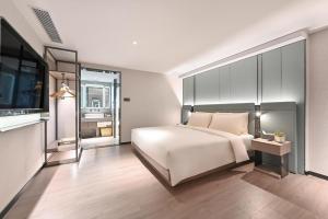 a bedroom with a large white bed and a television at Atour S Hotel Beijing Sanlitun Guoan in Beijing