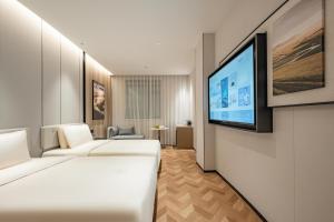 上海市にあるAtour Hotel Shanghai Center Lujiazuiのソファと薄型テレビが備わるホテルルームです。