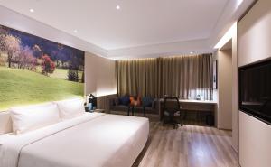 um quarto de hotel com uma grande cama branca e uma secretária em Atour Hotel International Convention and Exhibition Center Changchun em Changchun