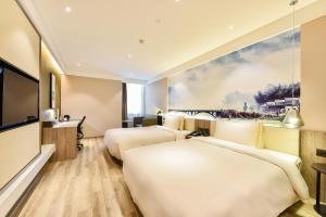 Atour Hotel Capital Airport Beijing في بكين: غرفة فندقية بسريرين وتلفزيون