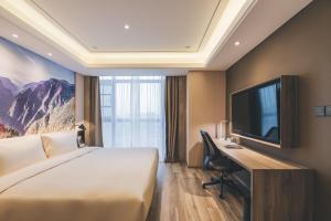 Pokój hotelowy z łóżkiem, biurkiem i telewizorem w obiekcie Atour Hotel Chongqiang Jiangbei Airport w mieście Chongqing