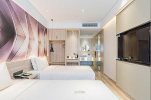 上海市にあるAtour Hotel Shanghai Hongqiao Korea Streetのベッド2台、薄型テレビが備わるホテルルームです。