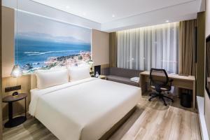 Atour Hotel Qingdao Fuzhou Road Sakura Town في تشينغداو: غرفة في الفندق مع سرير ومكتب