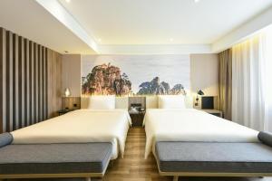 2 letti in una camera d'albergo con un dipinto sul muro di Atour Hotel Beijing Chaoyang Park a Pechino