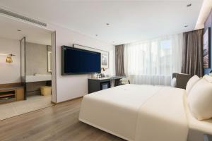 a hotel room with a large white bed and a television at Dalian Airport Yingke Road Atour Hotel in Dalian +46 photos