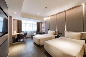 a hotel room with two beds and a desk at Atour Hotel Suzhou Guanqian Street in Suzhou