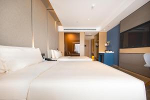 uma grande cama branca num quarto de hotel em Atour Hotel South Jinan Industrial Road CBD em Jinan