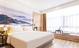 a bedroom with a large white bed and a large window at Atour Hotel Guangzhou Jiangtai Road Station in Guangzhou